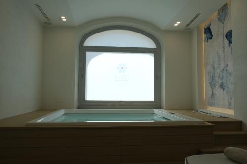 a bath tub in a room with a window at TANIT ROOMS & SPA in Villasimius