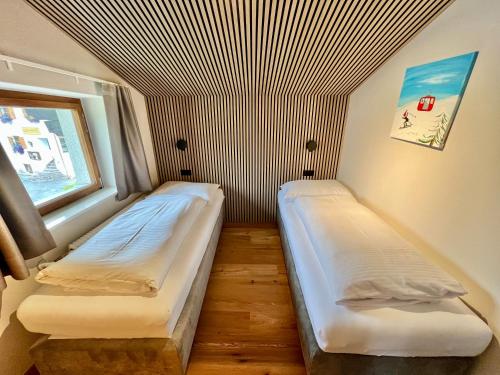 two beds in a small room with a window at Haus Schrofenstein in Lech am Arlberg