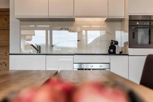 a kitchen with white cabinets and a wooden table at Apartments Chalet Anna in Ortisei
