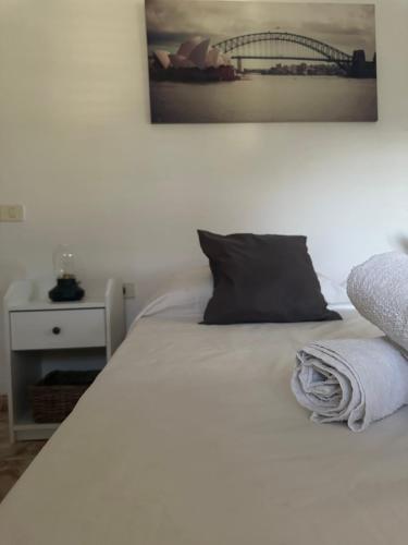 1 cama blanca con almohada negra y una foto en la pared en Apartamento Fortaleza en Vallehermoso