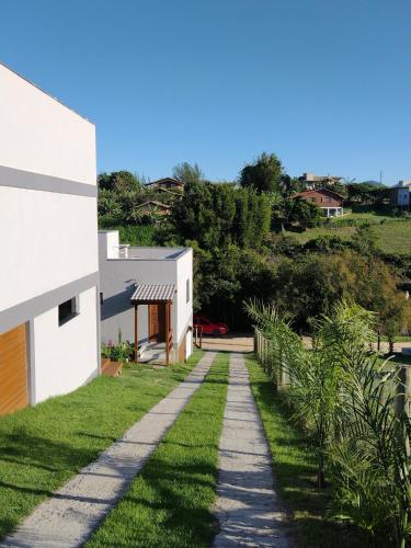 a walkway next to a house with grass at Suítes do Vale - Praia do Rosa in Imbituba