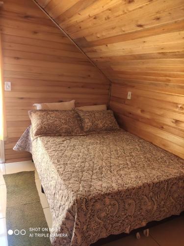 a bedroom with a bed in a wooden room at Cabanas das Araucárias in Urubici