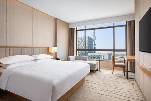 um quarto de hotel com uma cama e uma grande janela em Four Points by Sheraton Shanghai, Kangqiao em Xangai