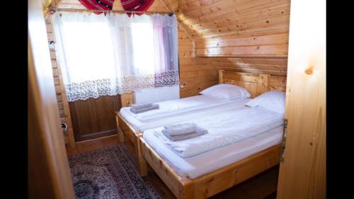 1 Schlafzimmer mit 2 Betten in einer Holzhütte in der Unterkunft Casa dintre Brazi in Arieşeni