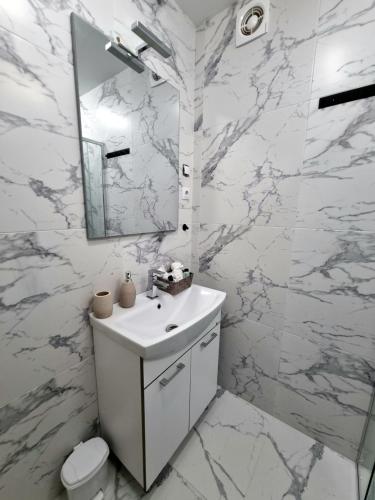 a white bathroom with a sink and a mirror at Muki House in Hunedoara