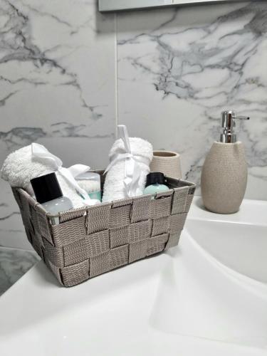 - un panier de serviettes et d'articles de toilette sur un comptoir de salle de bains dans l'établissement Muki House, à Hunedoara