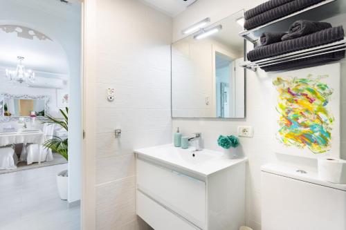 een witte badkamer met een wastafel en een spiegel bij EDEN RENTALS Sunset Seaviews Residence in Adeje