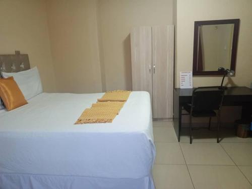 een slaapkamer met een bed, een bureau en een spiegel bij Beautiful Gate Guesthouse in Palatswe