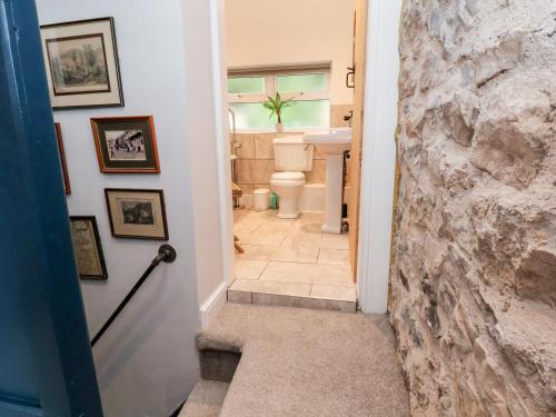 a hallway leading to a bathroom with a stone wall at Aster Cottage in Rhyl