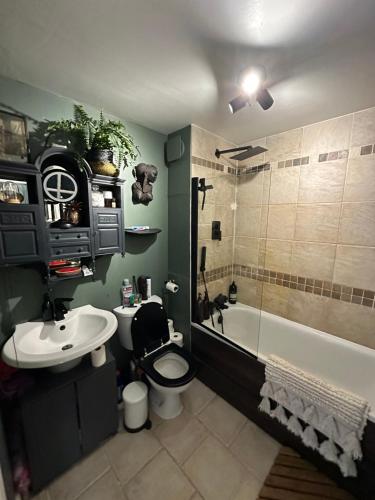 a bathroom with a toilet and a sink and a tub at Converted church in Beckenham