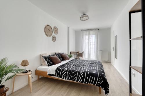 Schlafzimmer mit einem Bett mit einer schwarzen und weißen Bettdecke in der Unterkunft L'Ethnic Print - Paris Stade de France in Aubervilliers