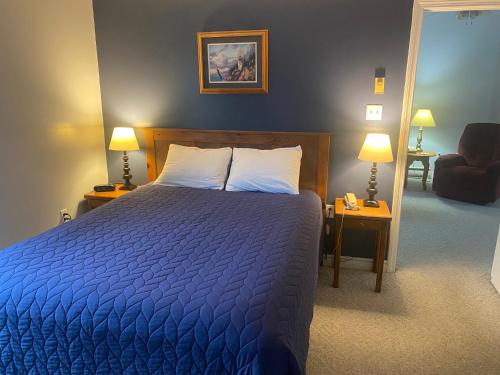 a bedroom with a blue bed with two lamps and a chair at Acadia Village Resort in Ellsworth