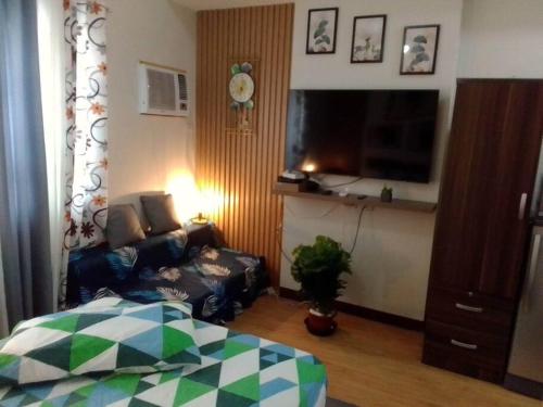 een woonkamer met een bed, een tv en een bank bij Affordable staycation @Mesaverte Residences cdo in Cagayan de Oro