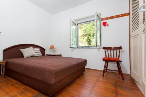 a bedroom with a bed and a chair and a window at Vila Tamara Apartmani in Bečići