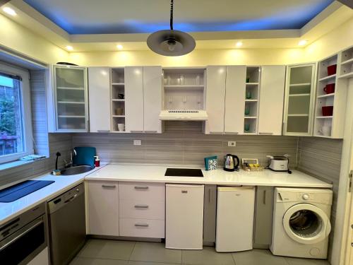 cocina con armarios blancos, lavadora y secadora en Central Elegance Estate, en Belgrado