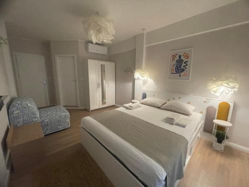 a bedroom with a large white bed and a chair at Sea Esta Apartment in Nea Peramos
