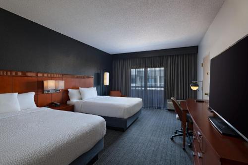 a hotel room with two beds and a desk at Courtyard by Marriott Dallas Plano Parkway at Preston Road in Plano