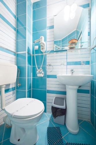 a blue bathroom with a toilet and a sink at Vila Bradet in Buşteni