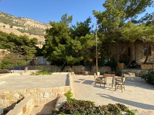a patio with chairs and a table and a tree at Dana Moon Hostel in Dana