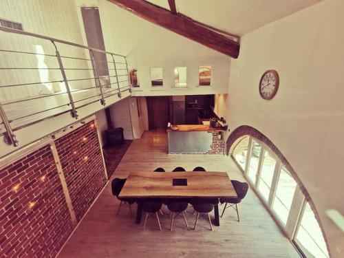 Un comedor con una mesa y sillas y un reloj. en Maison de village, jacuzzi, salle cinéma, en Valencin