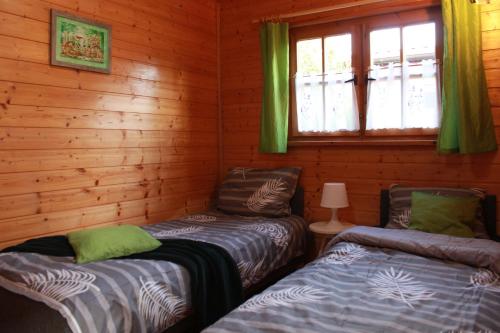 dwa łóżka w drewnianym domku z oknem w obiekcie Oaza Dąbek w mieście Dąbki
