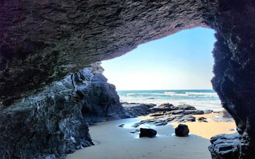 a cave on a beach with the ocean behind it at CORAM DEO SaltyWaves double en-suite rooms with sea views in Coffee Bay