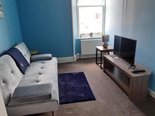 a living room with a couch and a flat screen tv at Bank House in Thurso