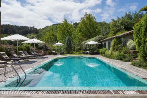una piscina con sillas y sombrillas en un patio en Hotel Iturregi, en Getaria