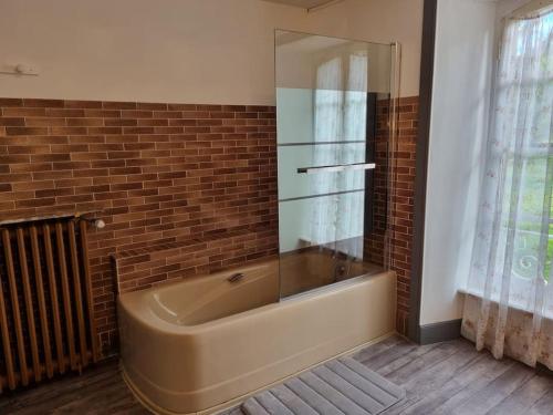 Cette chambre dispose d'une baignoire et d'un mur en briques. dans l'établissement Maison La Rase du Lac Cantal, à Menet