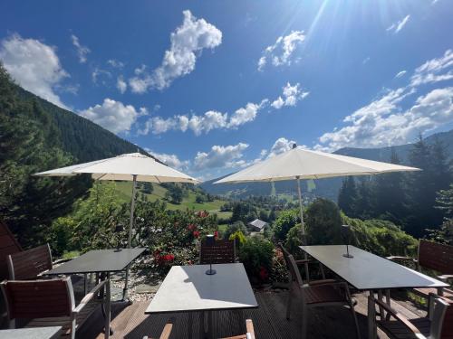 two tables and chairs with umbrellas on a deck at Pension & Appartements Ronacherhof -Mountain Hideaway Slopeside in Bad Kleinkirchheim