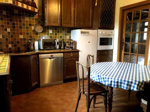 La cuisine est équipée d'une table, d'un réfrigérateur et d'un évier. dans l'établissement Maison La Rase du Lac Cantal, à Menet