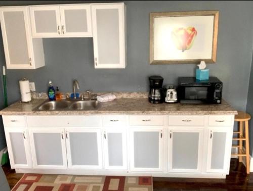 een keuken met witte kasten, een wastafel en een magnetron bij The House Hotels - Ridgewood Upper in Lakewood