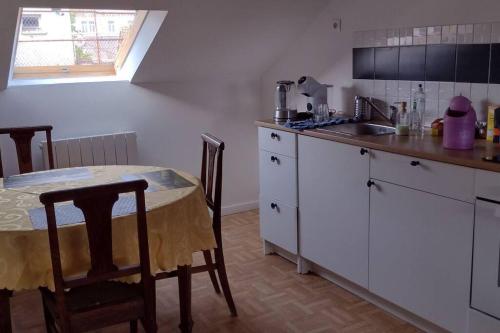 eine Küche mit einem Tisch, einem Waschbecken und einer Arbeitsplatte in der Unterkunft F3 centre ville de Gien in Gien