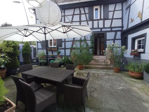 a patio with a table and chairs and an umbrella at La Cigogne dorée Gite de charme 4 étoiles in Schiltigheim