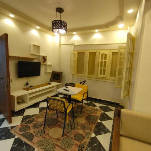 een woonkamer met een tafel en stoelen en een televisie bij شاليه الفرح in El Alamein