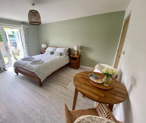 1 dormitorio con cama y mesa de madera en The Garden Room, en Delabole