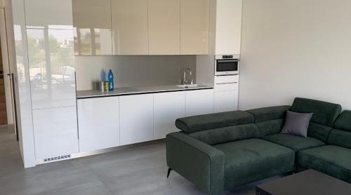 a living room with a green couch and a kitchen at Pri jazere - Golf rezort in Hrubá Borša