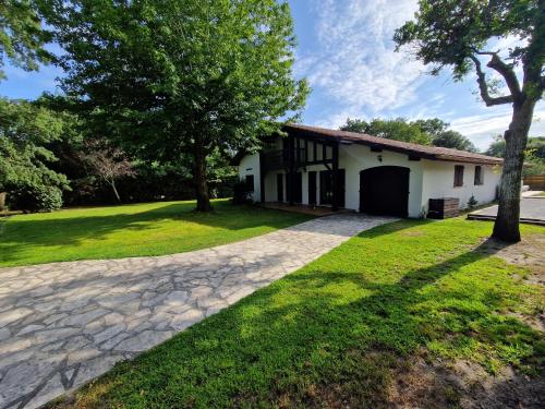 une maison avec un arbre et une allée dans l'établissement Villa 12 personnes Avec piscine et vélos Proche océan, à Moliets-et-Maa