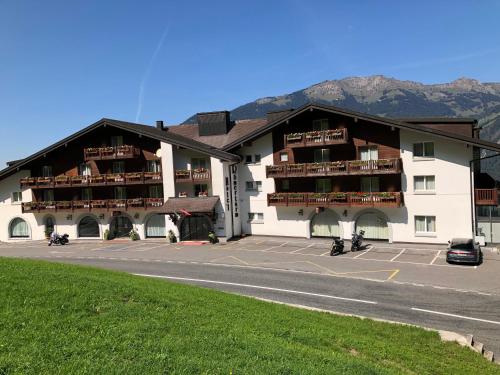 a large white building with a parking lot at Seminar- & Erlebnishotel RömerTurm in Filzbach