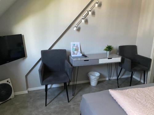 a bedroom with a desk with two chairs and a tv at Hotel Kellermann in Overath