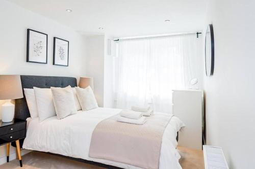 a white bedroom with a large bed with white pillows at Hidden Gem with En-Suites in West Hampstead in London