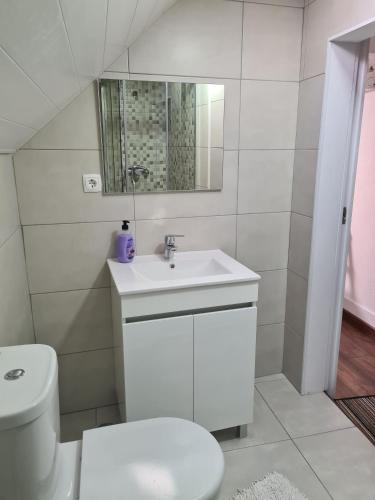 a white bathroom with a toilet and a sink at Glaciar Guest House in Manteigas