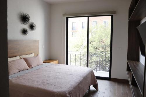 - une chambre avec un lit et une grande fenêtre dans l'établissement Residencias La Estación San Miguel de Allende, à San Miguel de Allende