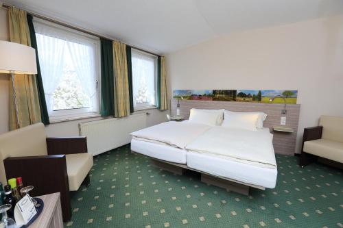 a hotel room with a large bed and a chair at Jeddinger Hof Land- und Seminarhotel in Visselhövede