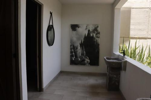 um corredor com um lavatório e uma imagem na parede em Residencias La Estación San Miguel de Allende em San Miguel de Allende