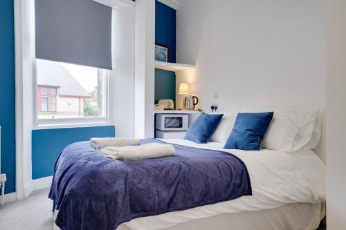 1 dormitorio con 1 cama grande y paredes azules en Homesly Guest Rooms, Comfortable En-suite Guest Rooms with Free Parking and Self Check-in, en Berwick-Upon-Tweed