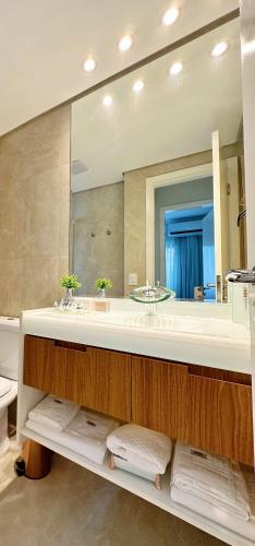 a bathroom with a sink and a large mirror at Sao Paulo Ibirapuera Privilege - Suite Deluxe in Sao Paulo