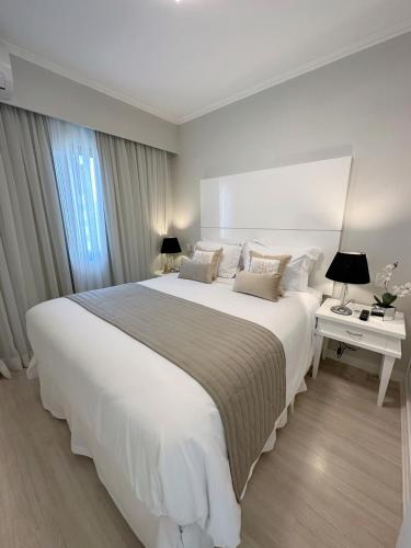 a white bedroom with a large white bed and a window at Sao Paulo Ibirapuera Privilege - Suite Deluxe in Sao Paulo