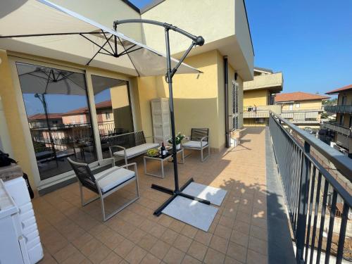 a patio with chairs and an umbrella on a balcony at Maison de Cheeramie - Tourist Apartments Tra Mare e Etna in Mascali
