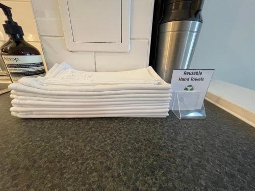 a stack of white towels next to a bottle of wine at Peloton Organic Health Apartment in Angel, Old Street, Islington in London